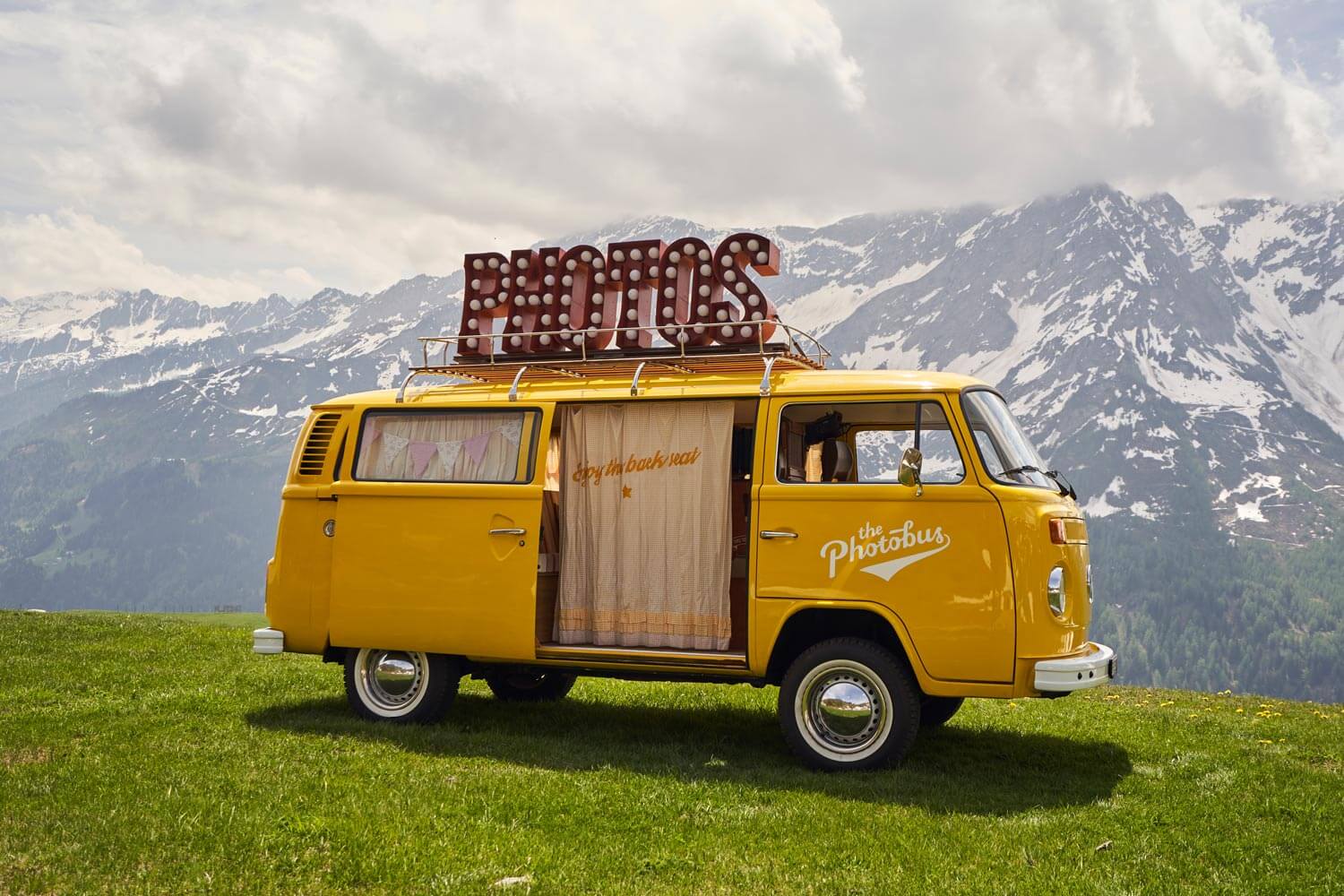 Gelber VW Photobus vor Bergkulisse