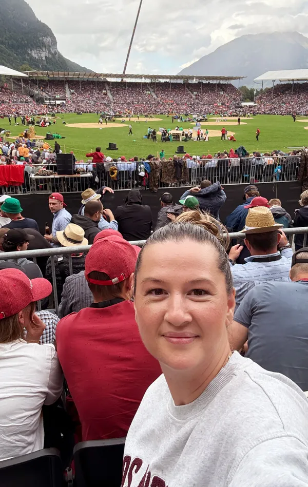Joëlle von Photobus Schweiz in der Arena am ESAF 2025 in Mollis, umgeben von Schwingfans und mit Blick auf das Sägemehl im Schwingring