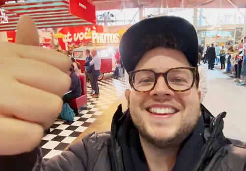 Selfie von Lorenz von Photobus Schweiz an der IGEHO Basel 2025 mit der roten Lady in Red im Hintergrund am Transgourmet-Retro-Stand.