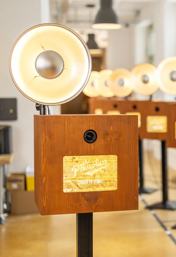 Detaillierte Ansicht der mobilen Fotobox mit professionellem Studioblitz (Beauty Dish), elegantem Holzdesign und sichtbar verbauter Kamera-Technik.