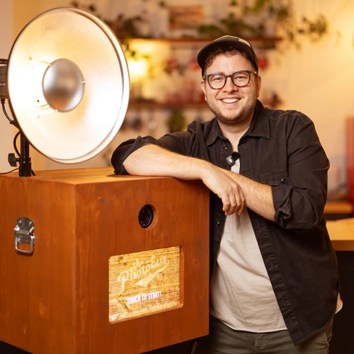 Portrait von Lorenz Walter - GeschĂ€ftsfĂŒhrer und Inhaber von Photobus posiert mit einer Fotobox im Photobus Studio in Wetzikon ZĂŒrich