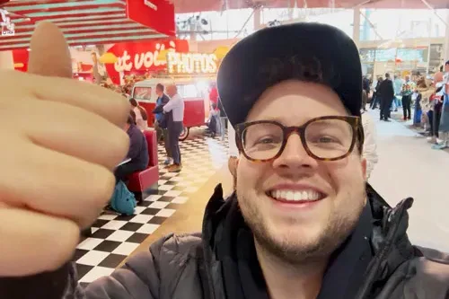 Selfie von Lorenz von Photobus Schweiz an der IGEHO Basel 2025 mit der roten Lady in Red im Hintergrund am Transgourmet-Retro-Stand.