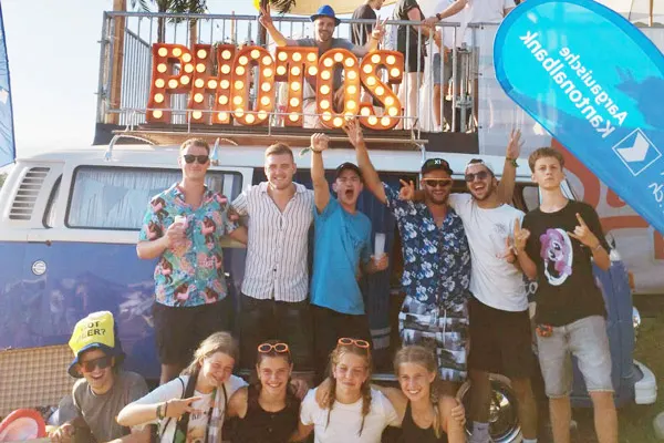 Photobus-Erfolgs-Strategie: Grosse Gruppe posiert vor dem VW-Bus mit beleuchtetem Photos-Schriftzug bei einem Sommer-Event.