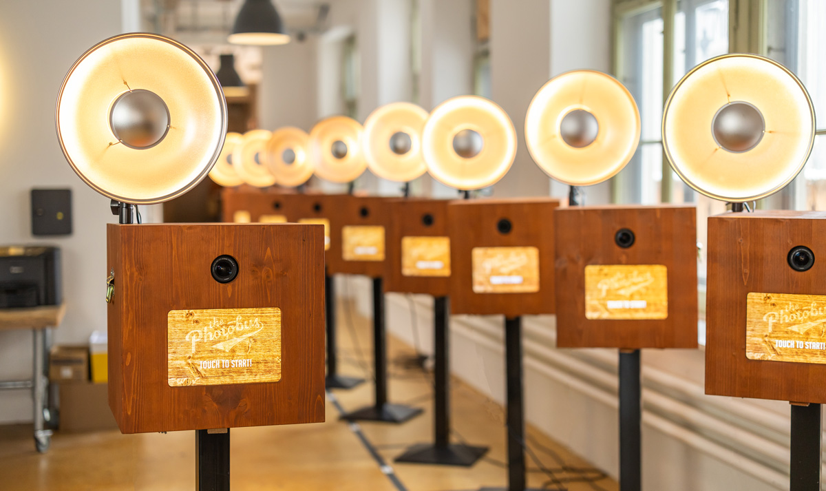 Eine Reihe von über zehn handgefertigten Retro-Fotoboxen aus Holz mit professionellen Studioblitzen in einem hellen Lagerraum von Photobus Schweiz.