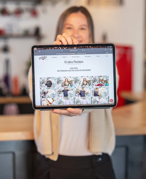 Joëlle Sahli hält ein Tablet mit der passwortgeschützten Photobus Online-Galerie und Foto-Downloads in den Händen.