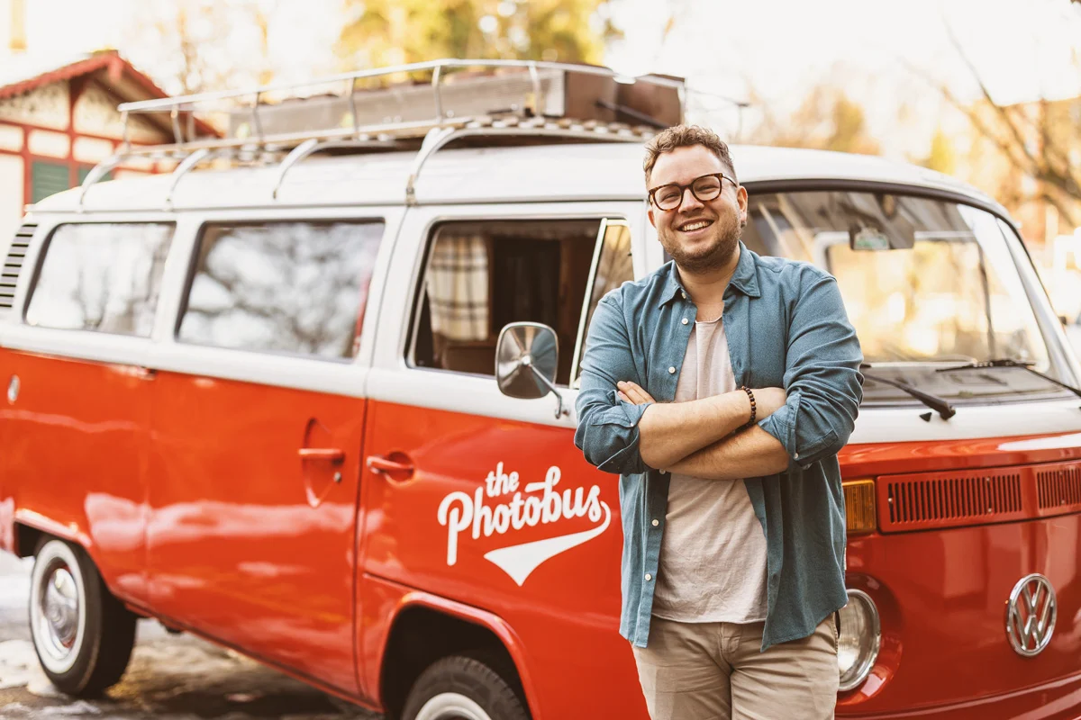 Lorenz Walter, Gründer von Photobus Schweiz und Experte für Fotobox-Systeme, steht vor einem restaurierten VW Photobus.