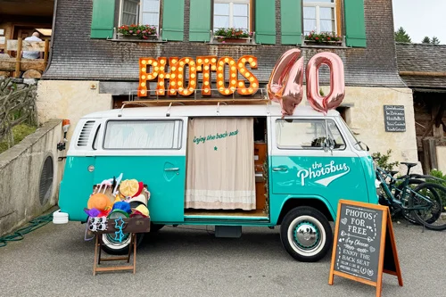 Mintgrüner VW Photobus mit Zahlen-Luftballon 40 und leuchtendem PHOTOS-Schriftzug als Fotobox für einen 40. Geburtstag in der Schweiz