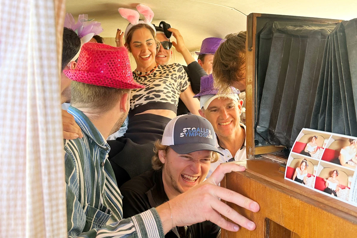 Lachende Gruppe im Innern des Photobus beim JGA mit Requisiten wie Hasenohren und Hüten sowie frisch gedrucktem Fotobox-Foto