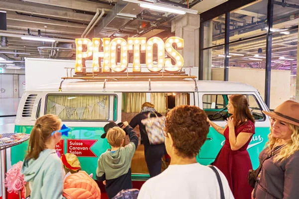 Mintgrüner VW Bus als Fotobox am Suisse Caravan Salon in Bern umringt von Besuchern.