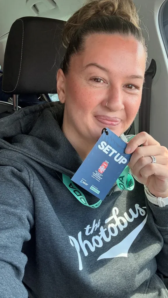 Joëlle von The Photobus mit offiziellem Setup-Badge der IIHF Eishockey-WM 2026 in der Schweiz