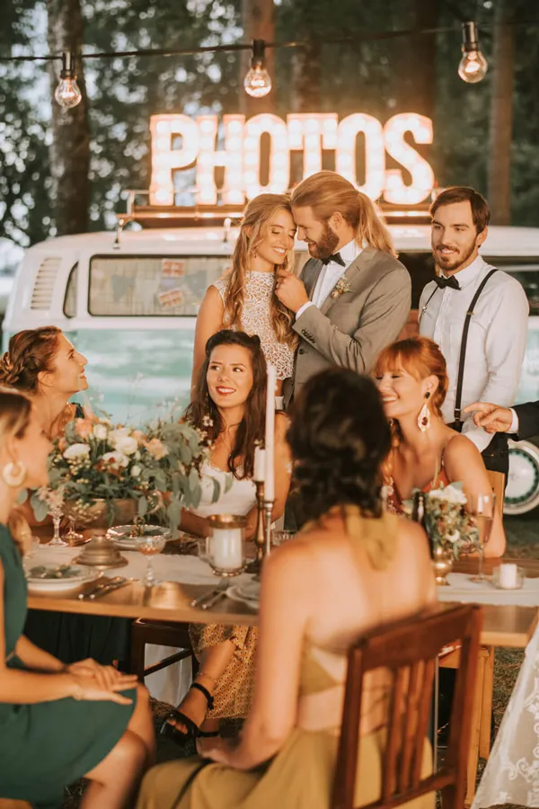 Photobus als Fotobox an der Hochzeit mit Gästen am Tisch und leuchtendem PHOTOS Schild